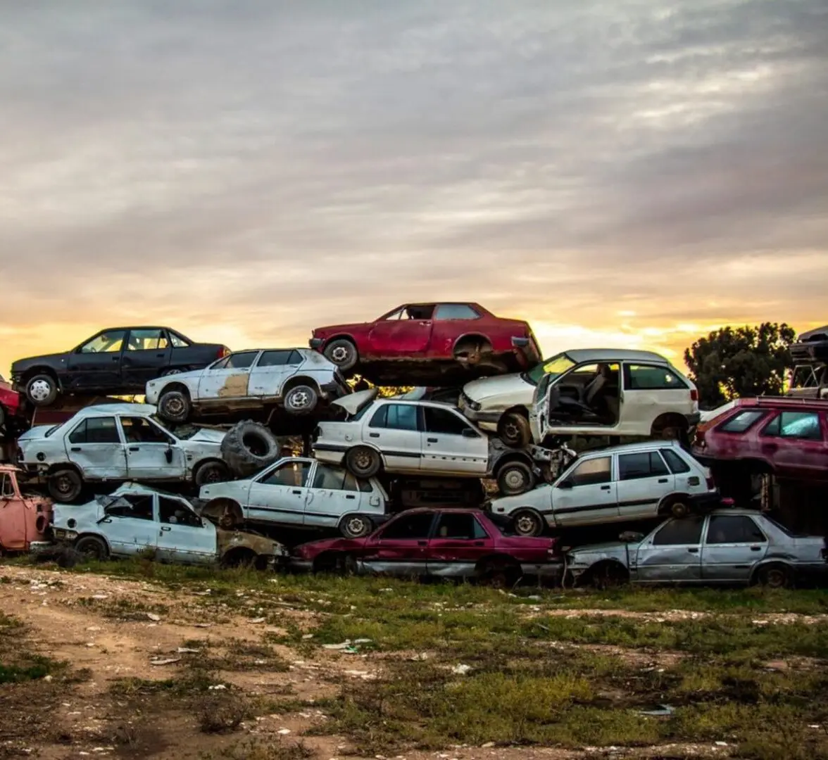 A pile of cars that are in the grass.